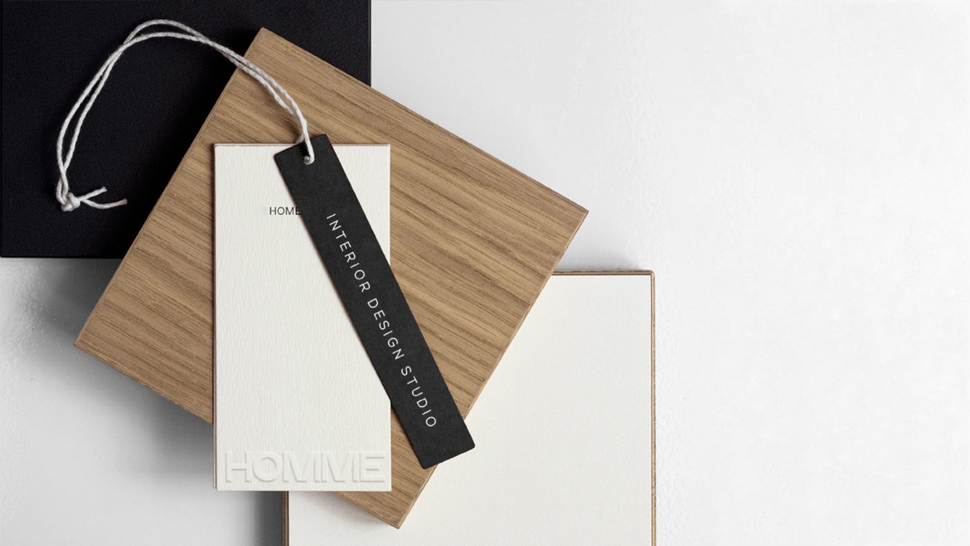 Black Interior Design Studio tag on an oak sample and a white card with a debossed wordmark
