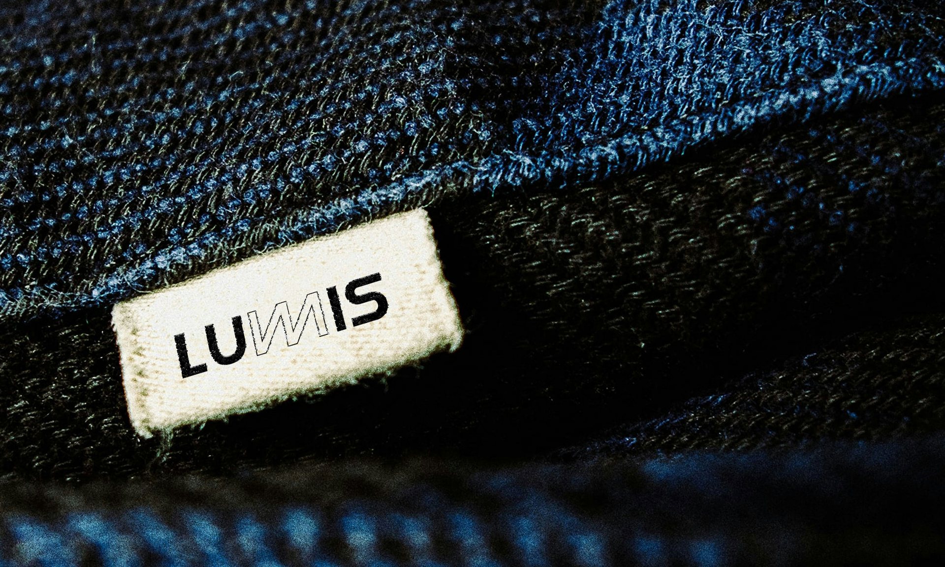 A woven Lumis label stitched inside a dark denim jacket