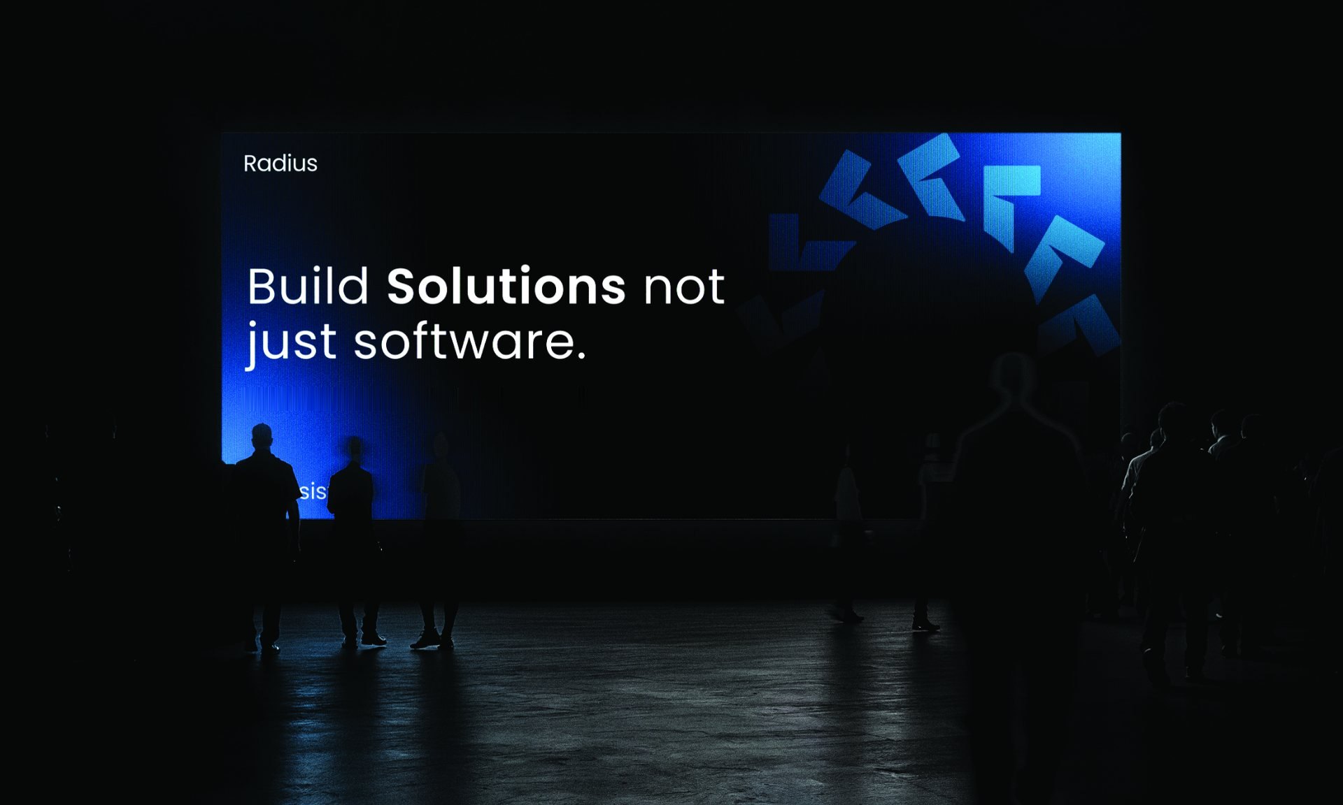 A crowd in front of a large screen reading Build solutions not just software