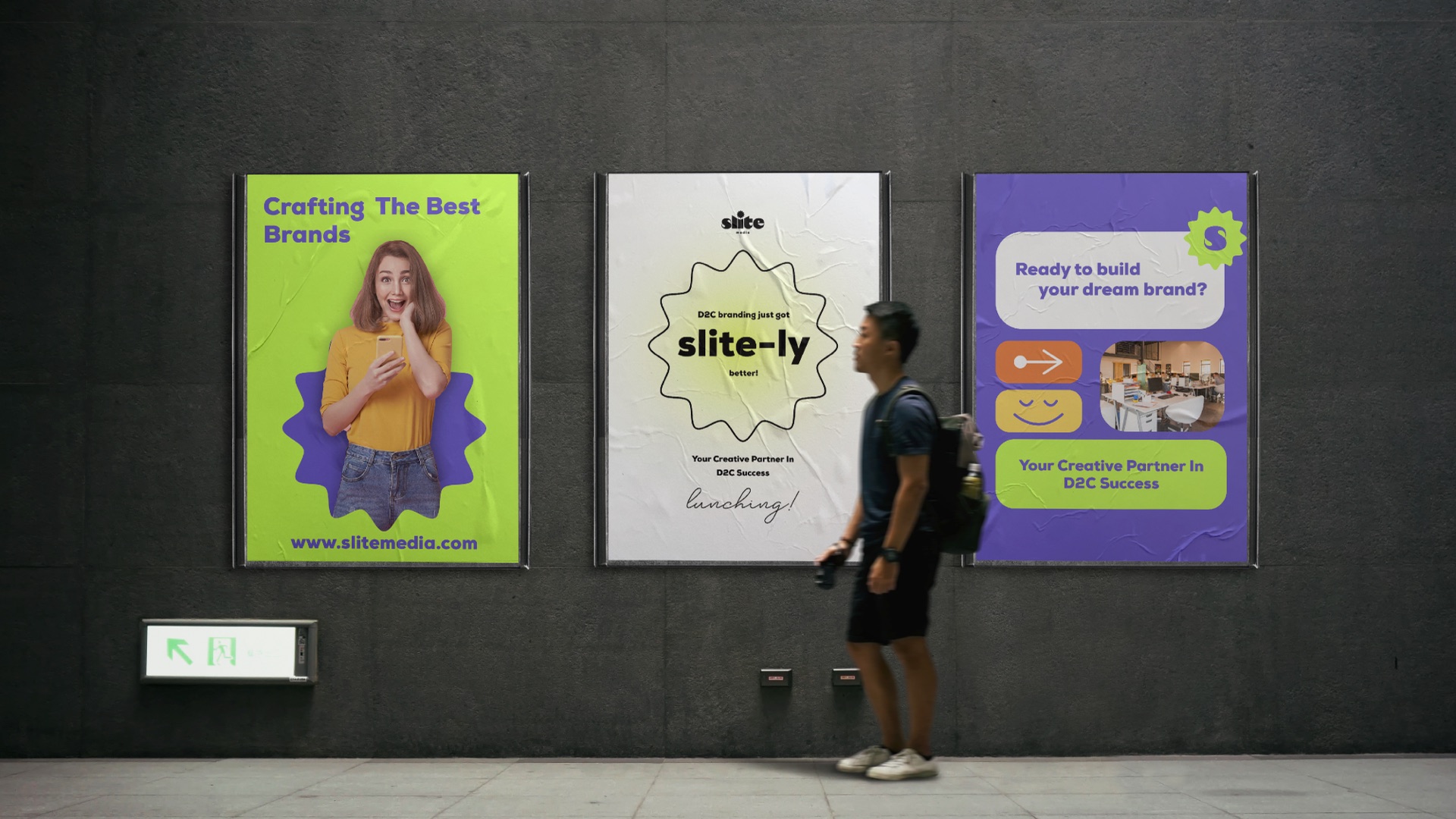 Three Slite posters on a dark wall with a man walking past