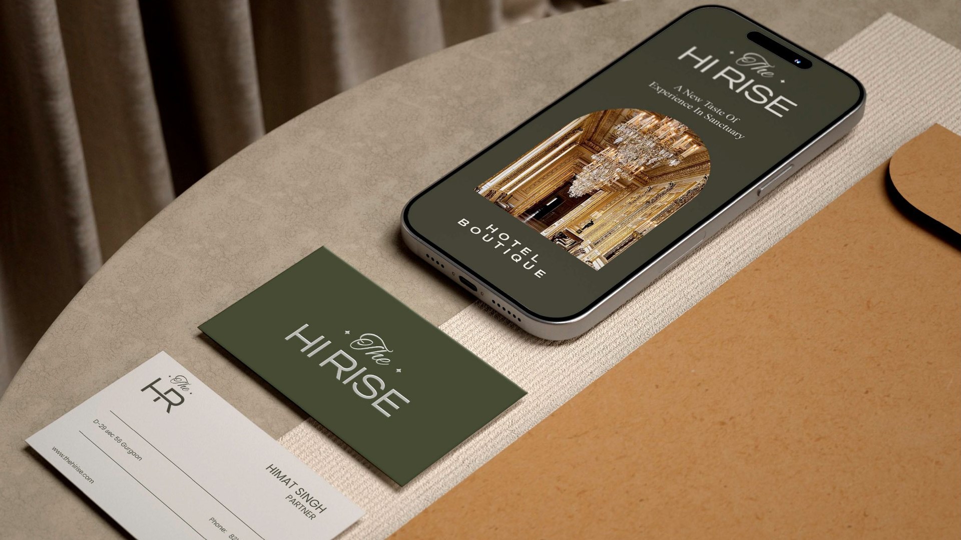 A phone, an olive business card and a monogram card on a round wooden table