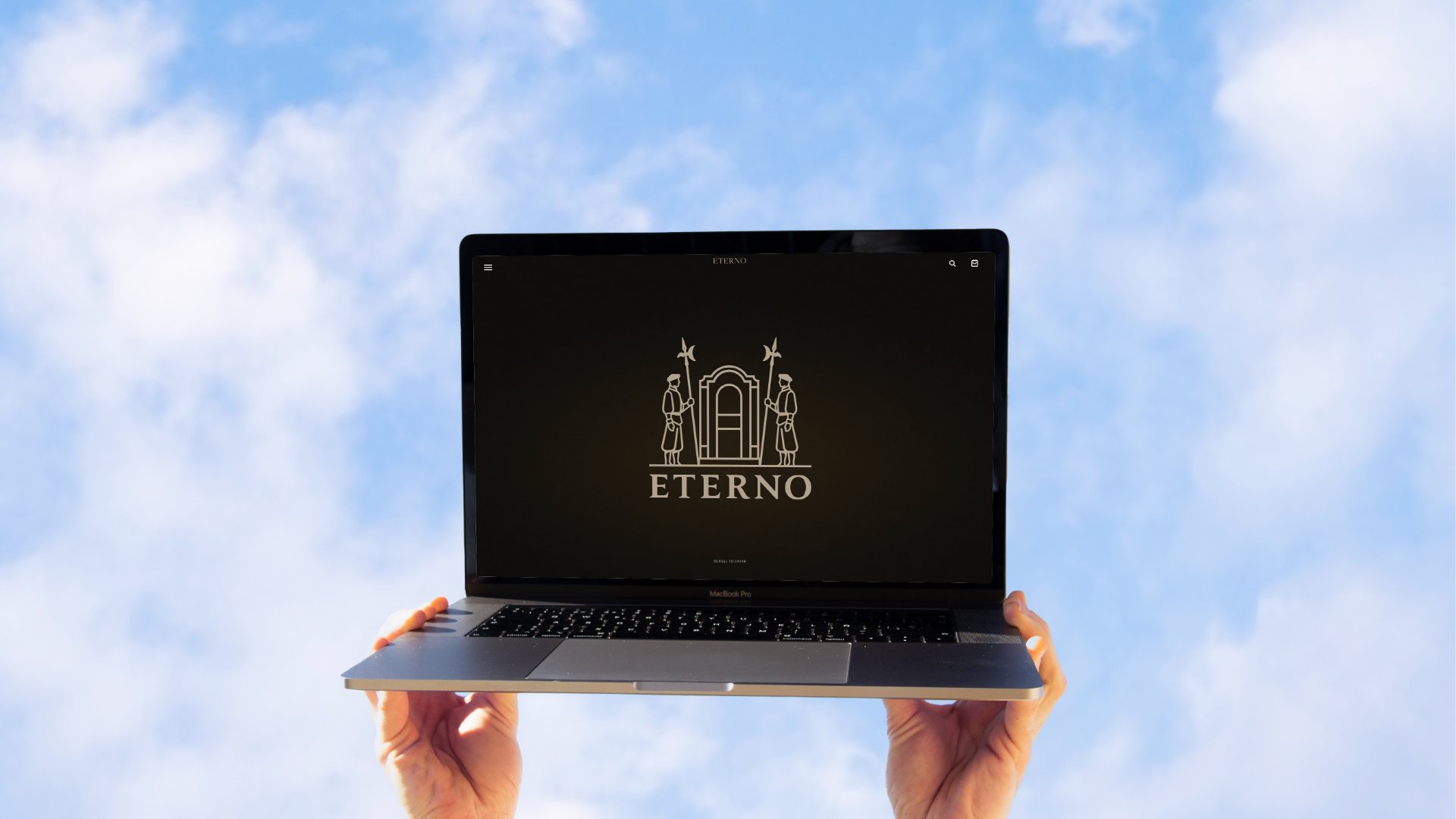 The crest on a laptop screen held up against the sky