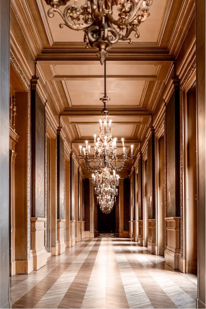 A wood panelled corridor with a row of chandeliers