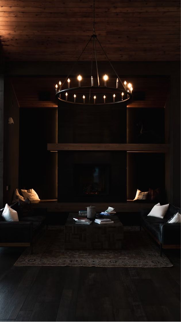 A dark lounge with sofas under a ring chandelier