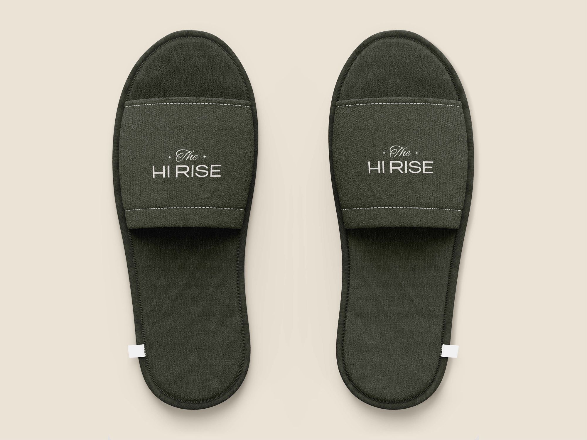 A pair of olive slippers with the logo in linen